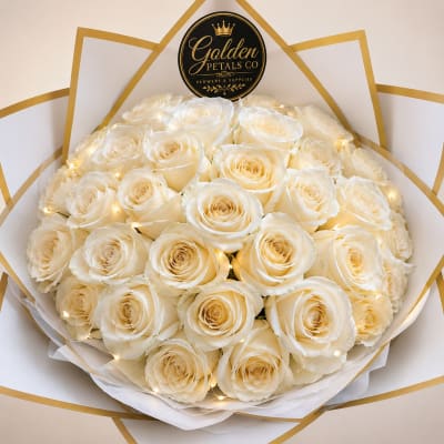 Bouquet of cream roses wrapped in white paper with gold trim