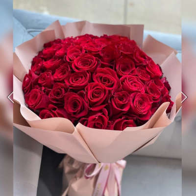 Large bouquet of red roses wrapped in pale pink paper