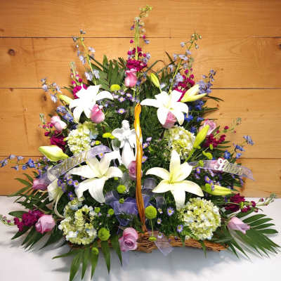 Large basket arrangement with white lilies, pink roses, and purple flowers