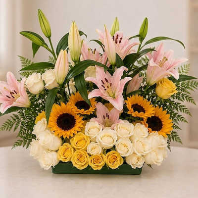 Arrangement of pink lilies, sunflowers, and cream roses in a rectangular vase