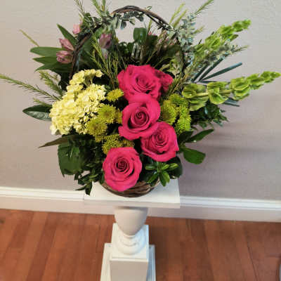 Basket arrangement with hot pink roses and pale yellow flowers