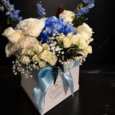 Blue and white floral arrangement in a white gift box with a ribbon