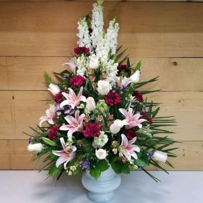 Tall floral arrangement in a white vase with pink lilies and white snapdragons