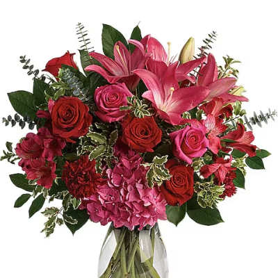 Bouquet of pink lilies, red roses, and hydrangea in a clear glass vase