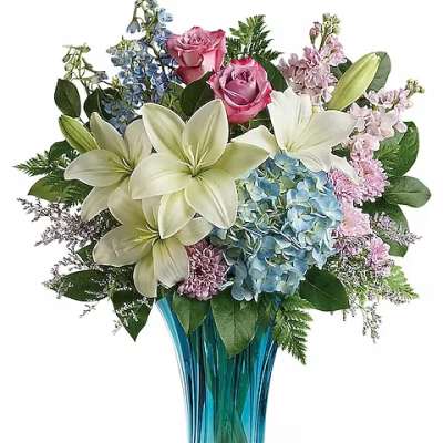 Bouquet of lilies, roses, hydrangeas, and blue flowers in a blue glass vase