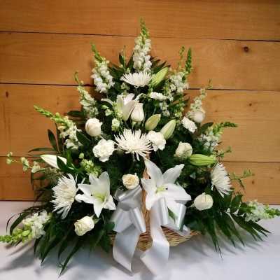 White lilies and chrysanthemums in a wicker basket with a silver ribbon