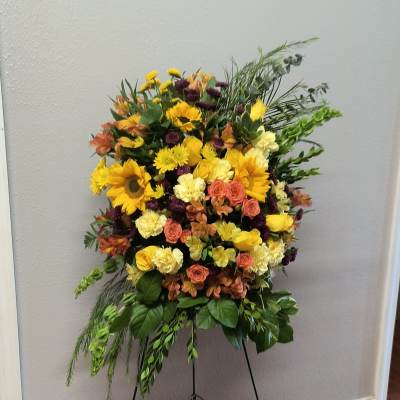Large standing floral spray with yellow, peach, and purple blooms on an easel