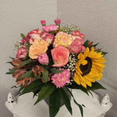 Mixed bouquet of roses, carnations, and a sunflower in a vase