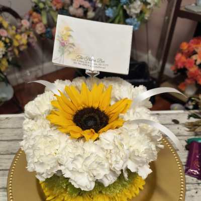 Sunflower and white carnation arrangement on a gold charger plate