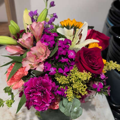 Mixed bouquet with roses, lilies, carnations, and purple filler flowers in a vase