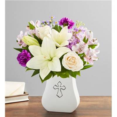 White lilies and roses in a white vase with a cross emblem