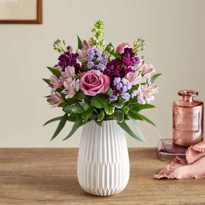 Mixed pink and purple flower arrangement with a rose and alstroemeria in a white ceramic vase