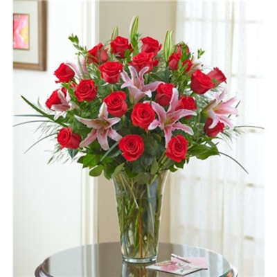 Red roses and pink lilies arranged in a clear glass vase.