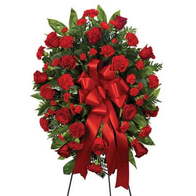 Red rose and carnation standing spray with a red ribbon
