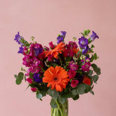 Bright mixed bouquet in a clear glass vase with orange and purple flowers