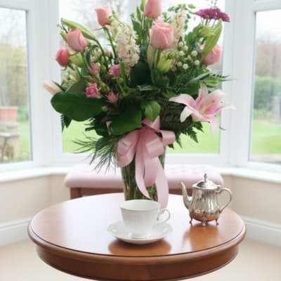 Pink and white floral arrangement in a clear glass vase on a table