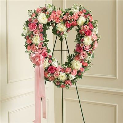 Heart-shaped floral wreath on an easel with pink and white flowers