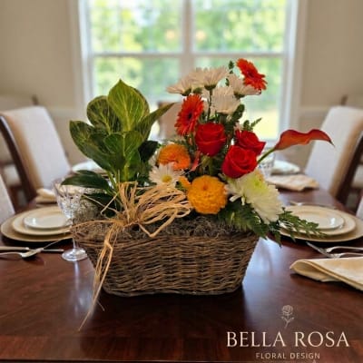 Basket arrangement with red roses, orange and white flowers, and a calla lily