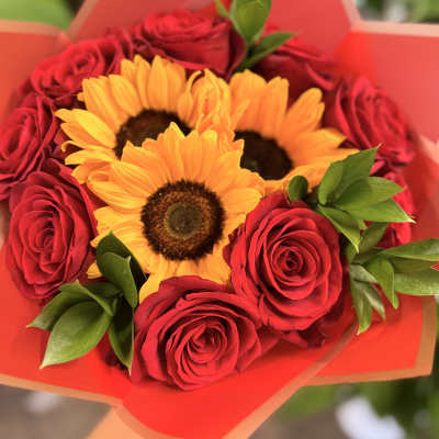 Bouquet of red roses and yellow sunflowers wrapped in orange paper