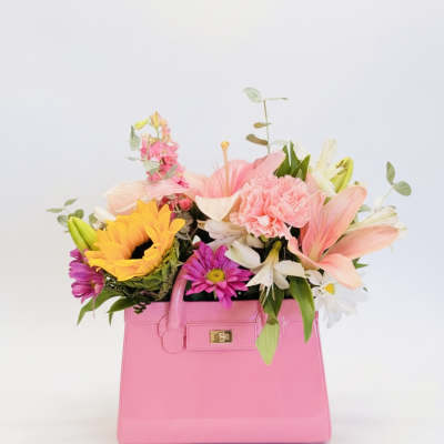 Pink handbag filled with colorful mixed flowers