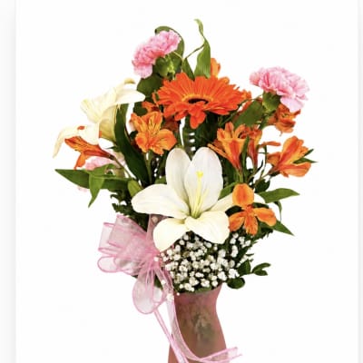 Bouquet of orange and pink flowers in a pink vase with a ribbon