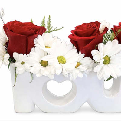 Red roses and white daisies arranged in a white LOVE container