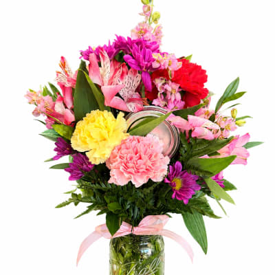 Colorful bouquet in a mason jar with pink, purple, yellow, and red blooms