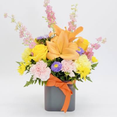 Colorful mixed bouquet with lilies, roses, and carnations in a gray vase