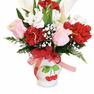 Bouquet of red carnations, pink roses, and white calla lilies in a white vase