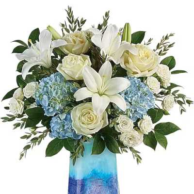 White lilies, roses, and blue hydrangeas in a blue glass vase