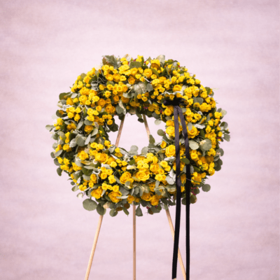 Large yellow rose wreath with black ribbon on a wooden easel stand