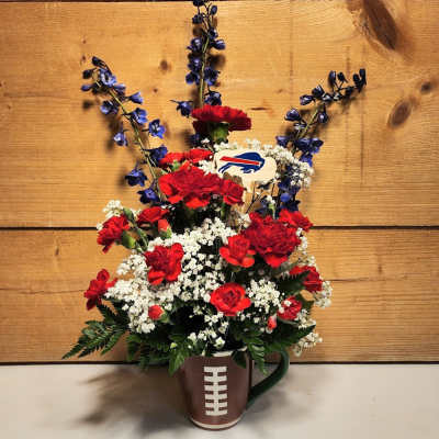 Red carnations and white filler flowers in a football mug with blue accents