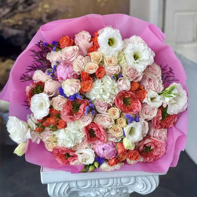 Large bouquet of pink, white, and coral flowers wrapped in bright pink paper
