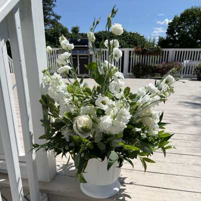 White floral arrangement in a white pedestal vase