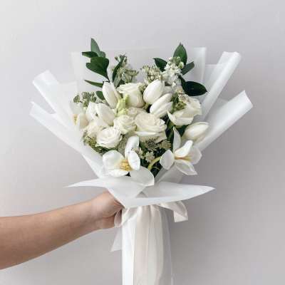 White bouquet with tulips, roses, and orchids wrapped in white paper