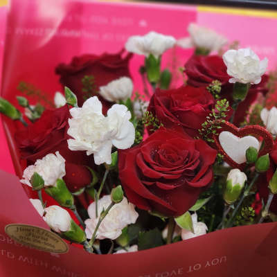 Bouquet of red roses and white carnations in pink wrapping