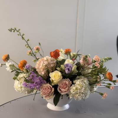 Mixed pastel floral arrangement in a white pedestal vase