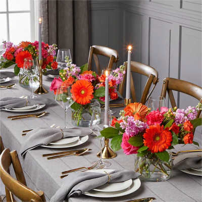 Bright mixed flower centerpieces on a set dining table with candles
