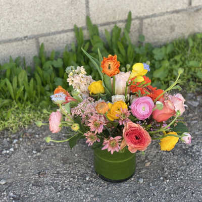 Mixed bouquet in a green vase with pink, yellow, orange, and white blooms