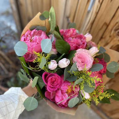 Pink mixed bouquet wrapped in brown paper with eucalyptus