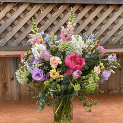 Mixed bouquet of pink, purple, white, and yellow flowers in a clear glass vase
