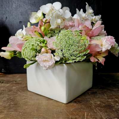 Pink and white floral arrangement in a white square vase
