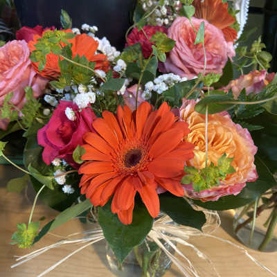 Mixed bouquet with orange gerbera daisies and pink roses in a glass vase