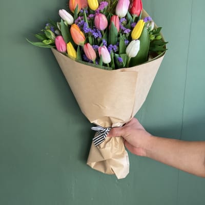 Bouquet of multicolored tulips wrapped in brown paper
