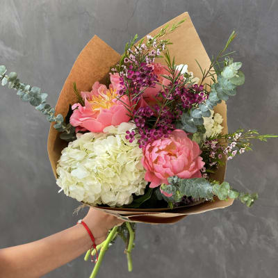 Pink peonies and white hydrangea bouquet with eucalyptus in brown paper
