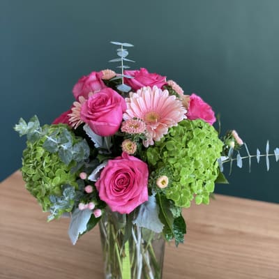 Pink roses and a pale gerbera daisy in a glass vase