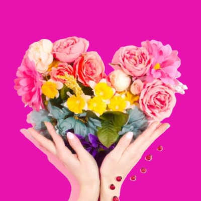 Heart-shaped bouquet of pink and yellow flowers held in two hands