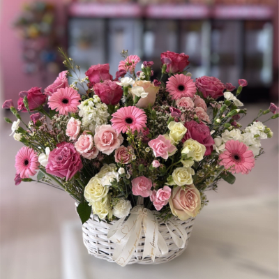 Pink and white mixed flower arrangement in a white basket