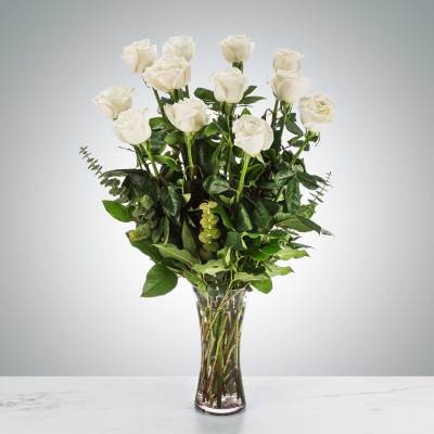 Tall bouquet of white roses in a clear glass vase