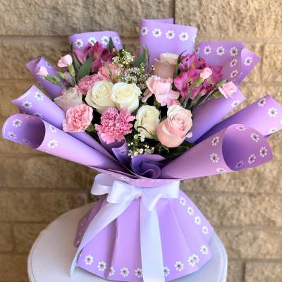 Bouquet of pink and white roses, carnations, and alstroemeria in purple wrap